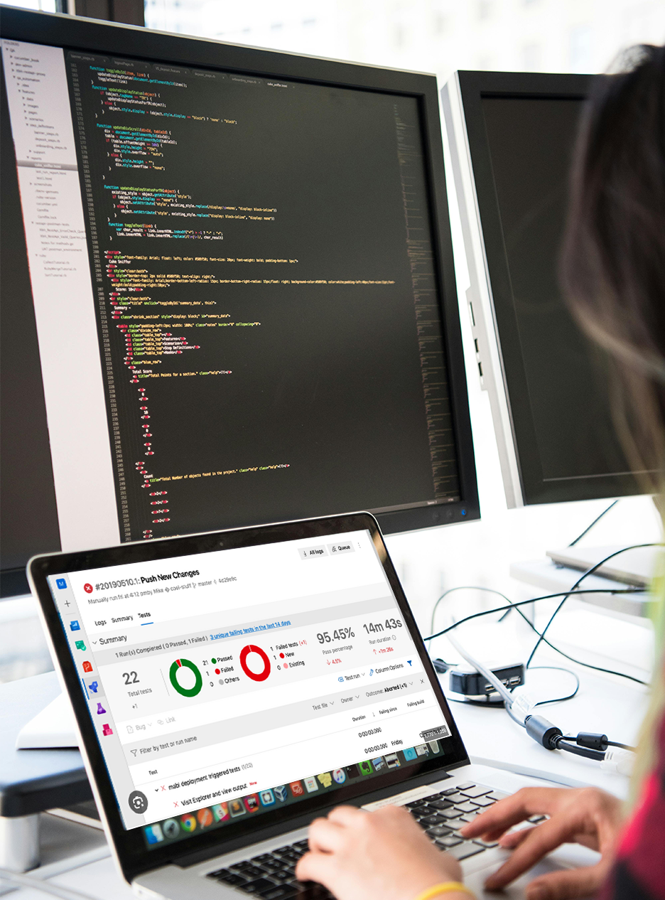 Woman Managing Production Deployment and Monitoring Code on Multi-Screen Workstation Woman working at a multi-screen workstation performing production deployment, monitoring system dashboards, and reviewing application code.